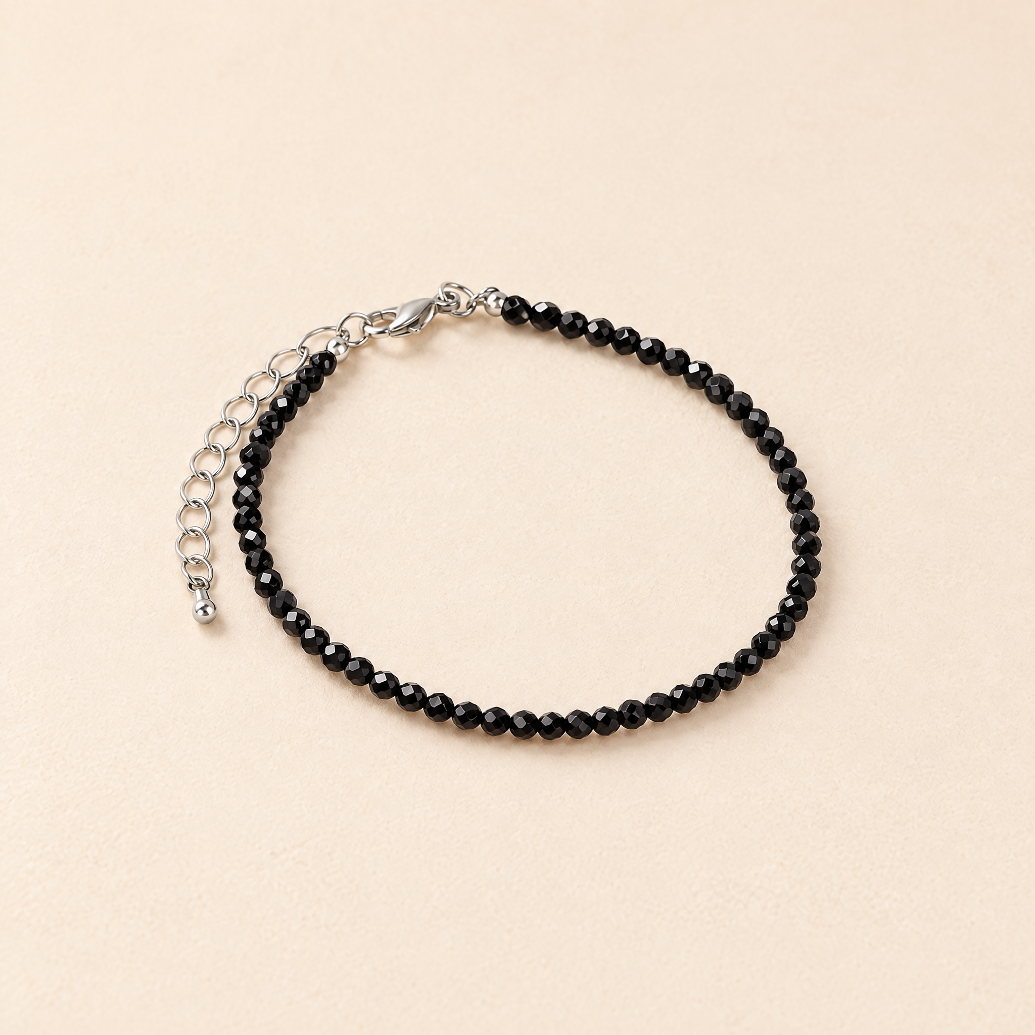 Soul Cleanse bracelet with tiny faceted black obsidian beads and silver clasp on a cream background